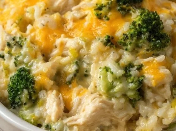 Cheesy broccoli chicken casserole with rice in a baking dish, garnished with herbs.