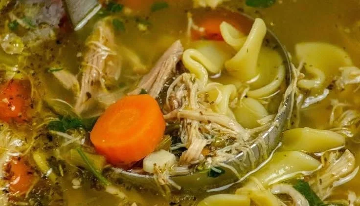 Bowl of easy leftover rotisserie chicken noodle soup garnished with herbs