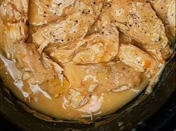 Cooked slow cooker chicken served with rich gravy in a bowl