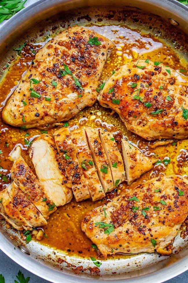 Delicious Garlic Butter Chicken sizzling in a pan garnished with herbs