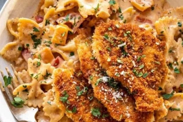 Creamy Parmesan Chicken Pasta served in a bowl with herbs and cheese garnish.